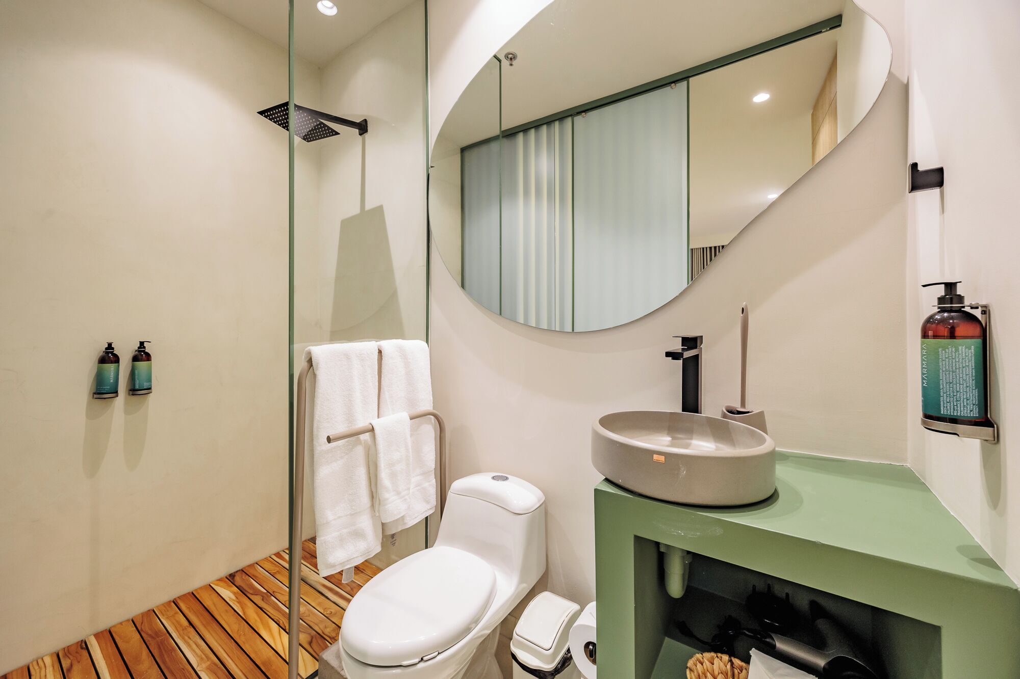 Ein modernes Badezimmer mit Toilette, Waschbecken, Dusche und Spiegel.