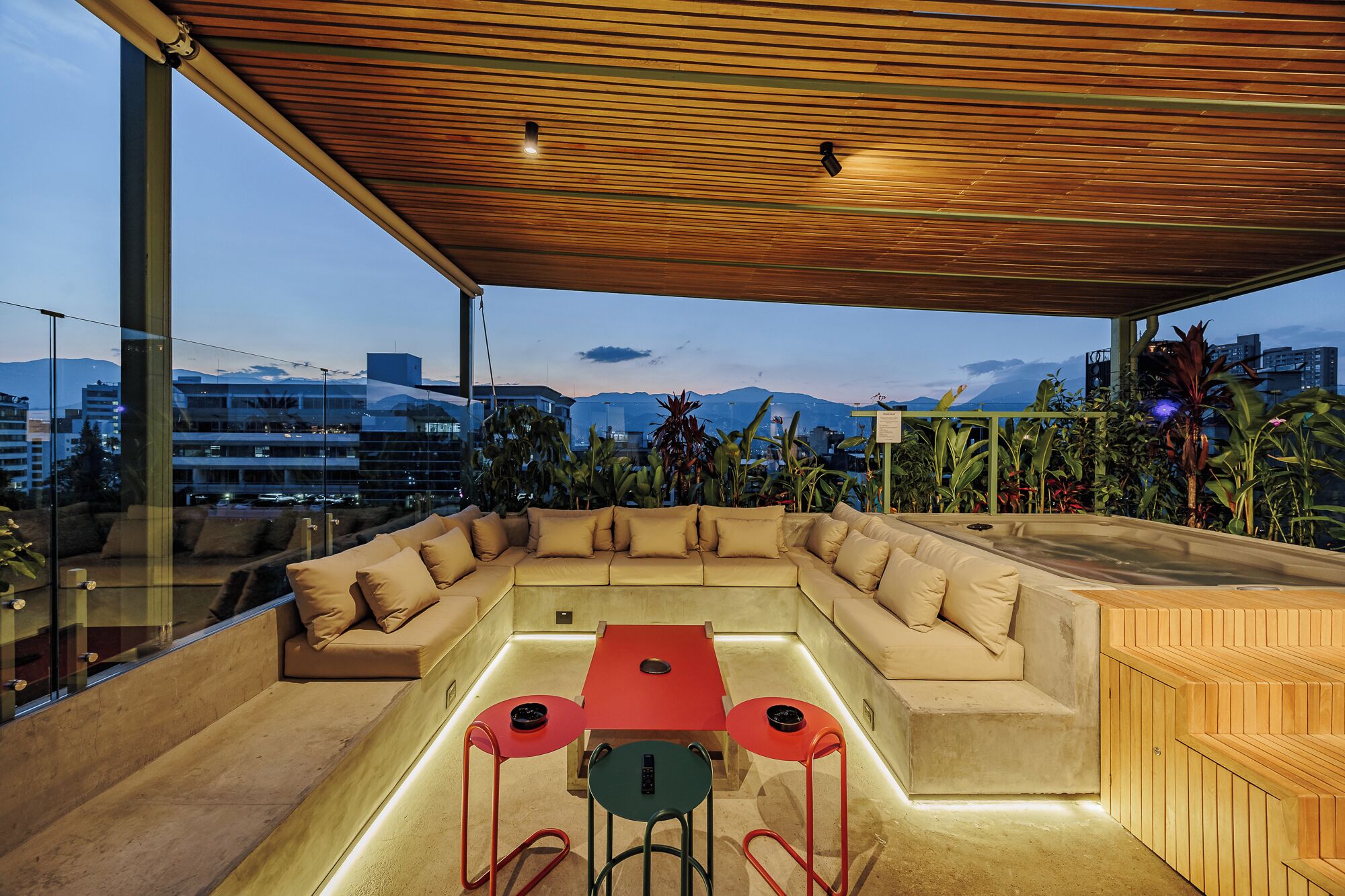 Un área de estar moderna al aire libre, con techo de madera, un sofá, una mesa y dos sillas.