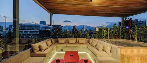 Un área de estar moderna al aire libre, con techo de madera, un sofá, una mesa y dos sillas.