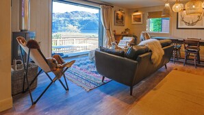 A cozy living room with a large window offering a mountain view, a fireplace, and a dining area.