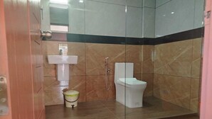 A bathroom with a shower, toilet, and sink. - Ocean Queen Palace Hotel (Kovalam)