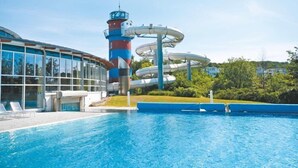 A swimming pool with a water slide and a building with large windows.