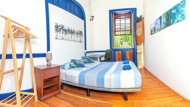 Une chambre à coucher comprenant un lit, un bureau, une chaise, une échelle en bois et une fenêtre donnant sur un paysage verdoyant.
