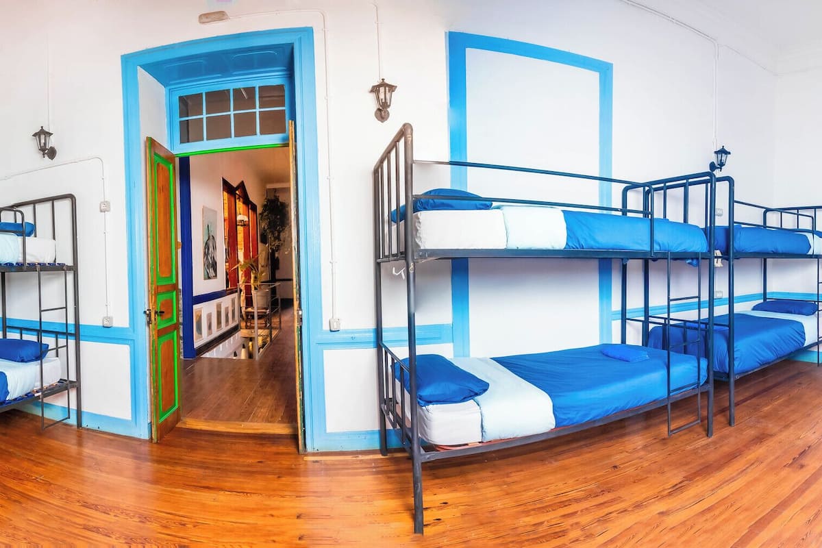 Quarto com beliches, piso de madeira e vista para o exterior.