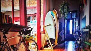 Un couloir avec un vélo, une planche de surf et une plante.