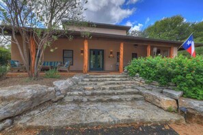 A two-story house with a stone staircase leading to the front door, a flag, and outdoor seating. - The Willows-Award Winning New York Magazine Home! (Fredericksburg)