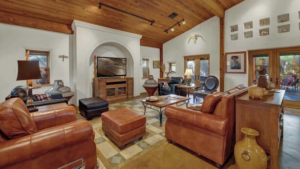 A spacious living room with leather sofas, a wooden ceiling, and a fireplace.
