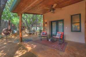 Un patio couvert avec deux chaises, une table et un barbecue.