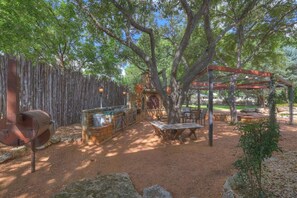 An outdoor patio with a grill, wooden tables, and a pergola. - The Willows-Award Winning New York Magazine Home! (Fredericksburg)