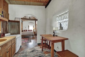 Una cocina funcional con armarios de madera, una mesa de comedor y un ventanal con cortina.