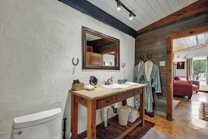 A rustic bathroom with a wooden vanity, a large mirror, and a toilet.