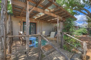 A rustic wooden deck with a covered area, outdoor furniture, and a natural surrounding.