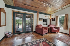 A room with a wooden ceiling, two red leather sofas, a small table, and a patterned rug.