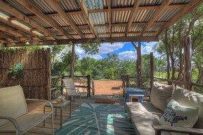An outdoor seating area with a wooden pergola, a sofa, a table, and chairs.