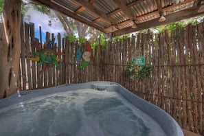 A hot tub area with a bamboo fence, a wooden ceiling, and a sign indicating quiet hours.
