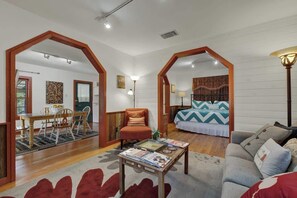 A spacious living area with a dining table, a sofa, and a bed with patterned bedding.