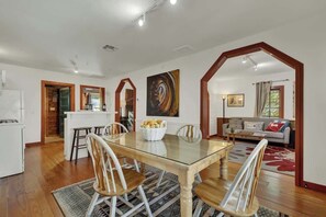 A dining area with a glass-top table, wooden chairs, and a basket of bread.