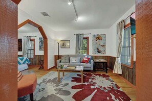 Ein gemütliches Wohnzimmer mit Sofa, Couchtisch und Kunstwerken an den Wänden.