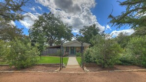 A house with a front porch, surrounded by trees and a well-maintained lawn.