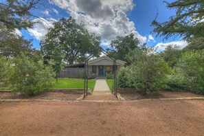 Ein Haus mit Veranda, umgeben von Bäumen und einem gepflegten Rasen.