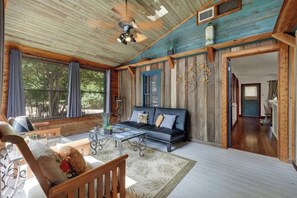 A spacious living area with a wooden ceiling, a sofa, a coffee table, and a view of the outdoors.
