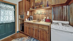 A kitchen with wooden cabinets, a stove, a sink, and a microwave.