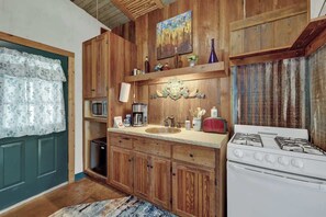 Una cocina con gabinetes de madera, estufa, fregadero y microondas.