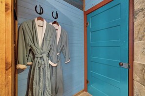 A room with a blue door and a wooden wall. There are two robes hanging on hooks. - Charming Retreat Duo,Hot-Tubs-Close to Marktplatz! (Fredericksburg)