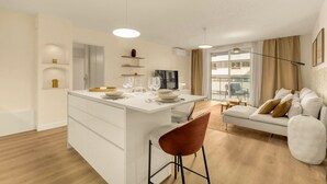 Un appartement moderne doté d’un îlot central dans la cuisine, d’un canapé et d’un coin repas.