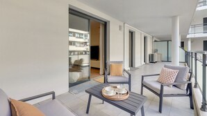 Un balcon moderne avec un canapé, des fauteuils et une table sur laquelle se trouve un plateau avec des tasses et des soucoupes.