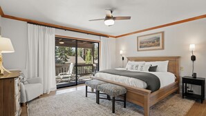 Une chambre avec un grand lit, un banc, un ventilateur de plafond et une vue sur l’extérieur.