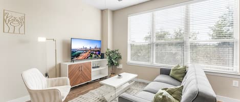 Een moderne woonkamer met een bank, een salontafel, een televisie en een plafondventilator.