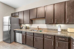 A modern kitchen with dark wooden cabinets, stainless steel appliances, and a granite countertop. - Fun Soco 1BR King Suite w Gympickleballlaundry (Austin)