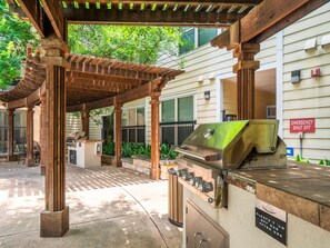 An outdoor barbecue area with a grill, a covered seating area, and a sign indicating emergency shut off. - Fun Soco 1BR King Suite w Gympickleballlaundry (Austin)