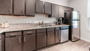 A modern kitchen with dark wooden cabinets, a stainless steel refrigerator, and a granite countertop. - Comfy Soco 1BR King Suite w Gympickleballlaundry (Austin)