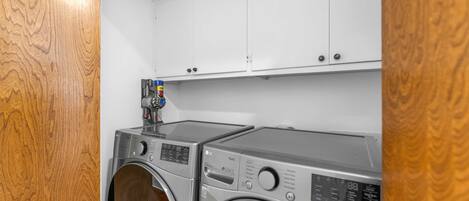 A laundry area with two front-loading washing machines and a cabinet above them.