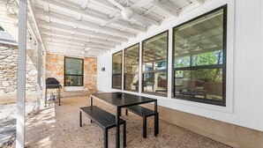 An outdoor patio with a stone wall, a grill, and a table with benches. - Close to Domain DT Shopping Chic Serene 3BR (Austin)