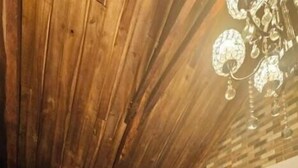 A room with a wooden ceiling, a white bathtub, and a chandelier.
