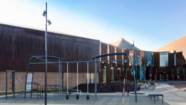 An outdoor area with exercise equipment, a building with a modern design, and a clear sky.