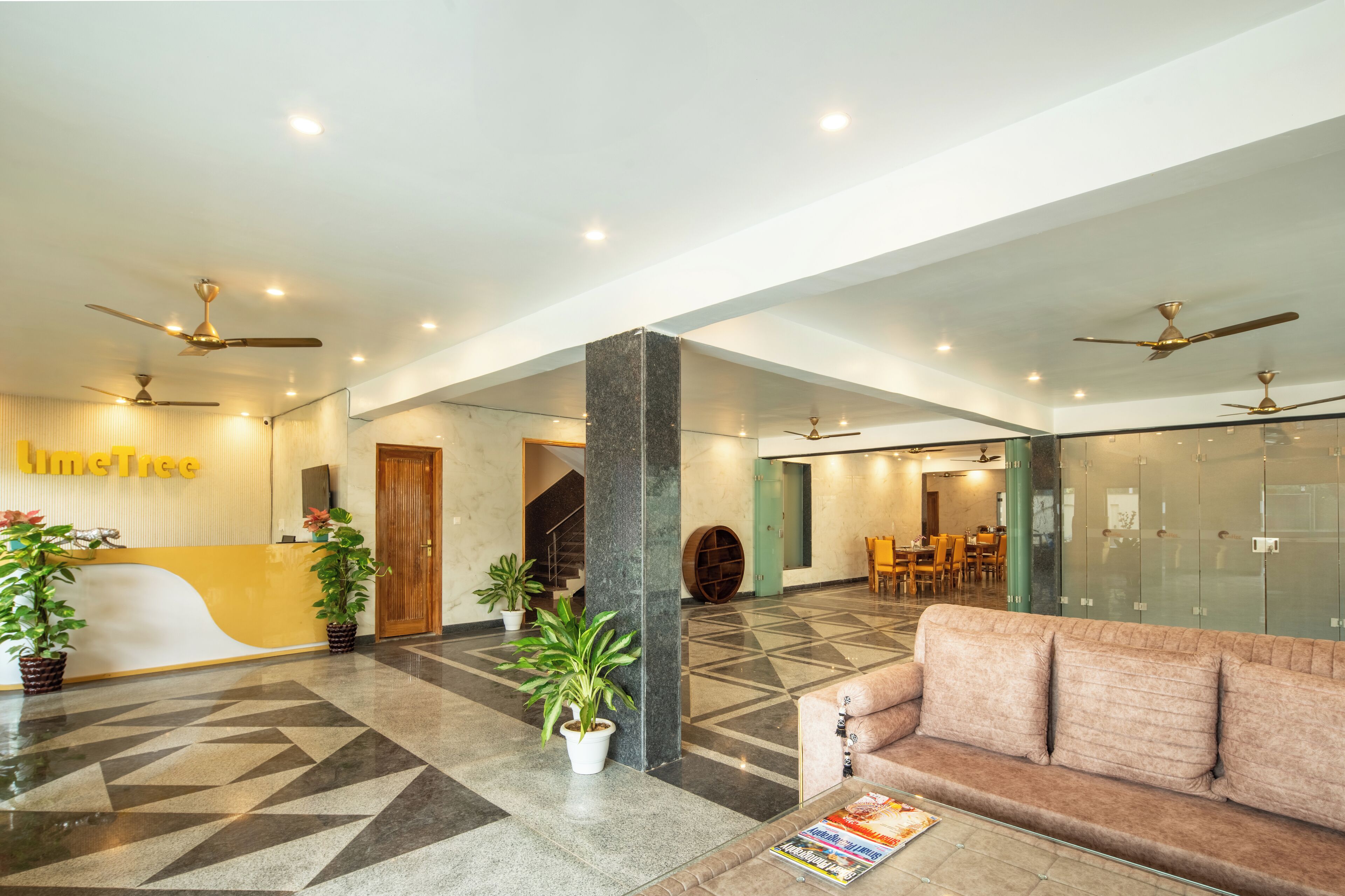 A modern lobby with a reception desk, seating area, and ceiling fans.