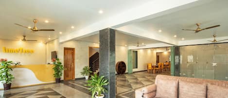 Eine moderne Lobby mit einer Rezeption, einer Sitzecke und Deckenventilatoren.