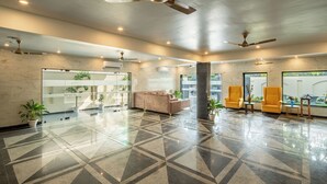A spacious lobby with a geometric tile floor, a reception desk, a sofa, and two armchairs. - Lime Tree Hotel & One BHK Serviced Apartment - Noida Sector 50 Metro (Noida)