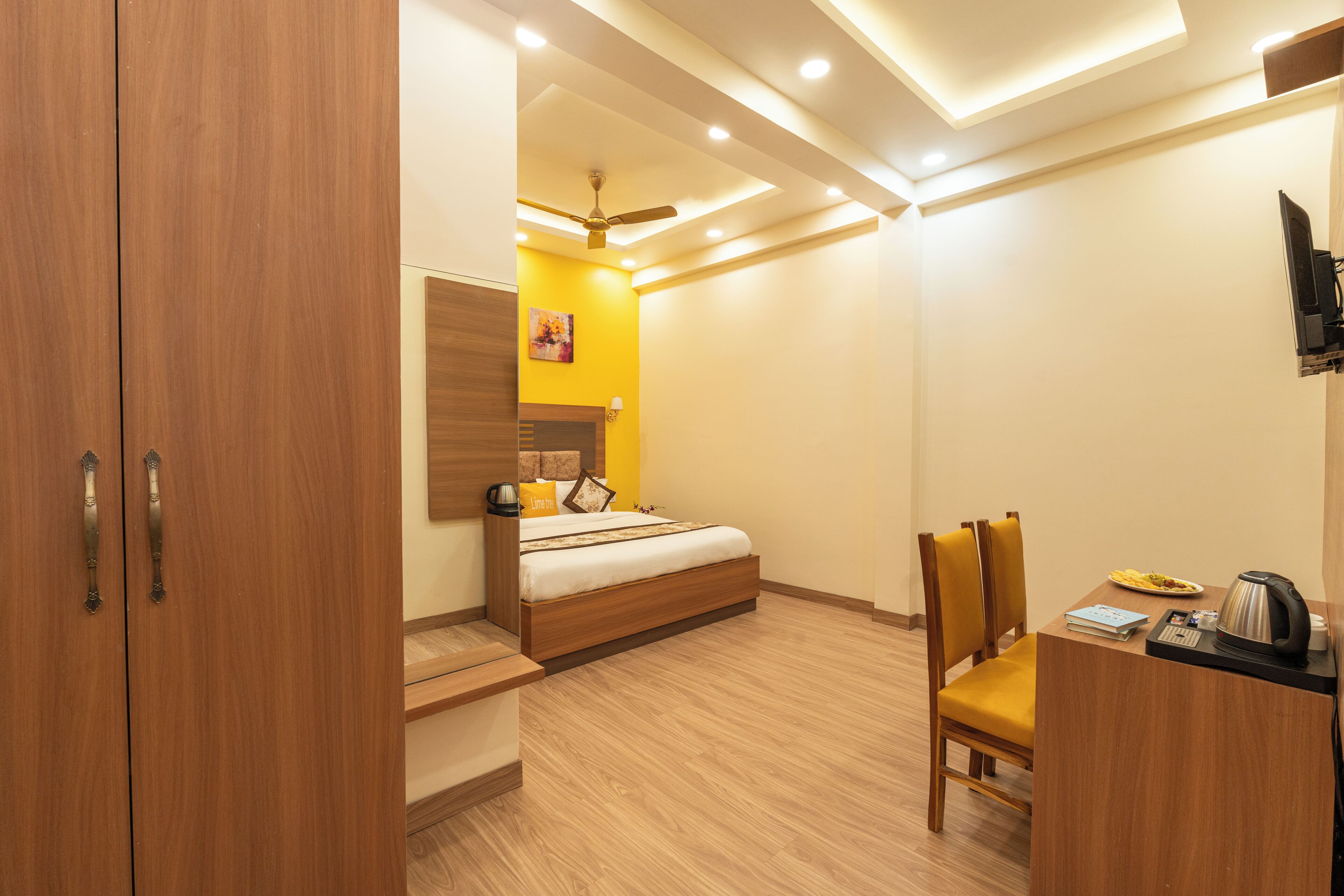 A hotel room with a bed, a desk, a chair, a TV, and a ceiling fan.