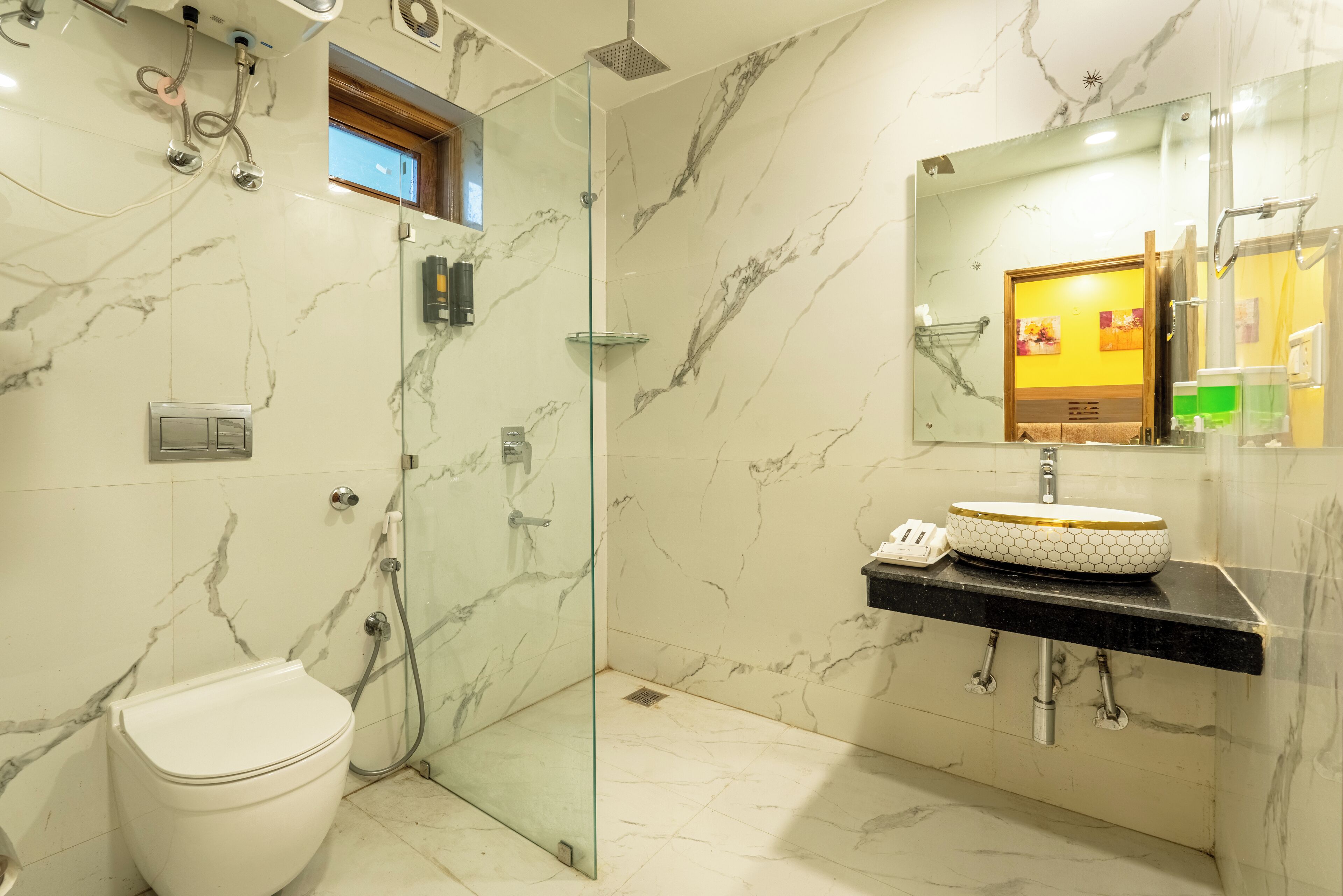 A modern bathroom with a glass-enclosed shower, a white toilet, and a black countertop with a gold-rimmed sink.