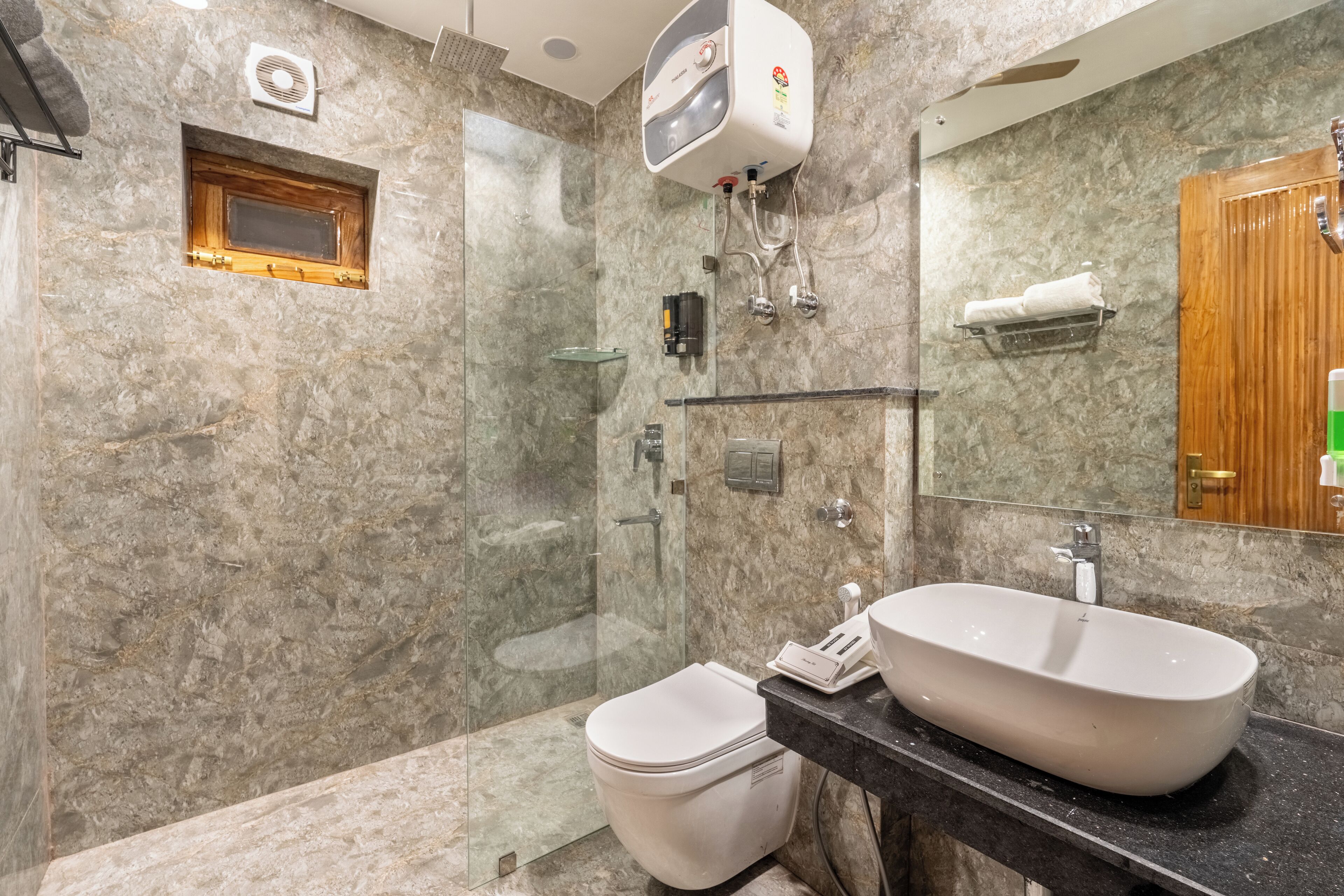 Un baño moderno con ducha de vidrio, inodoro blanco y un lavabo ovalado grande.