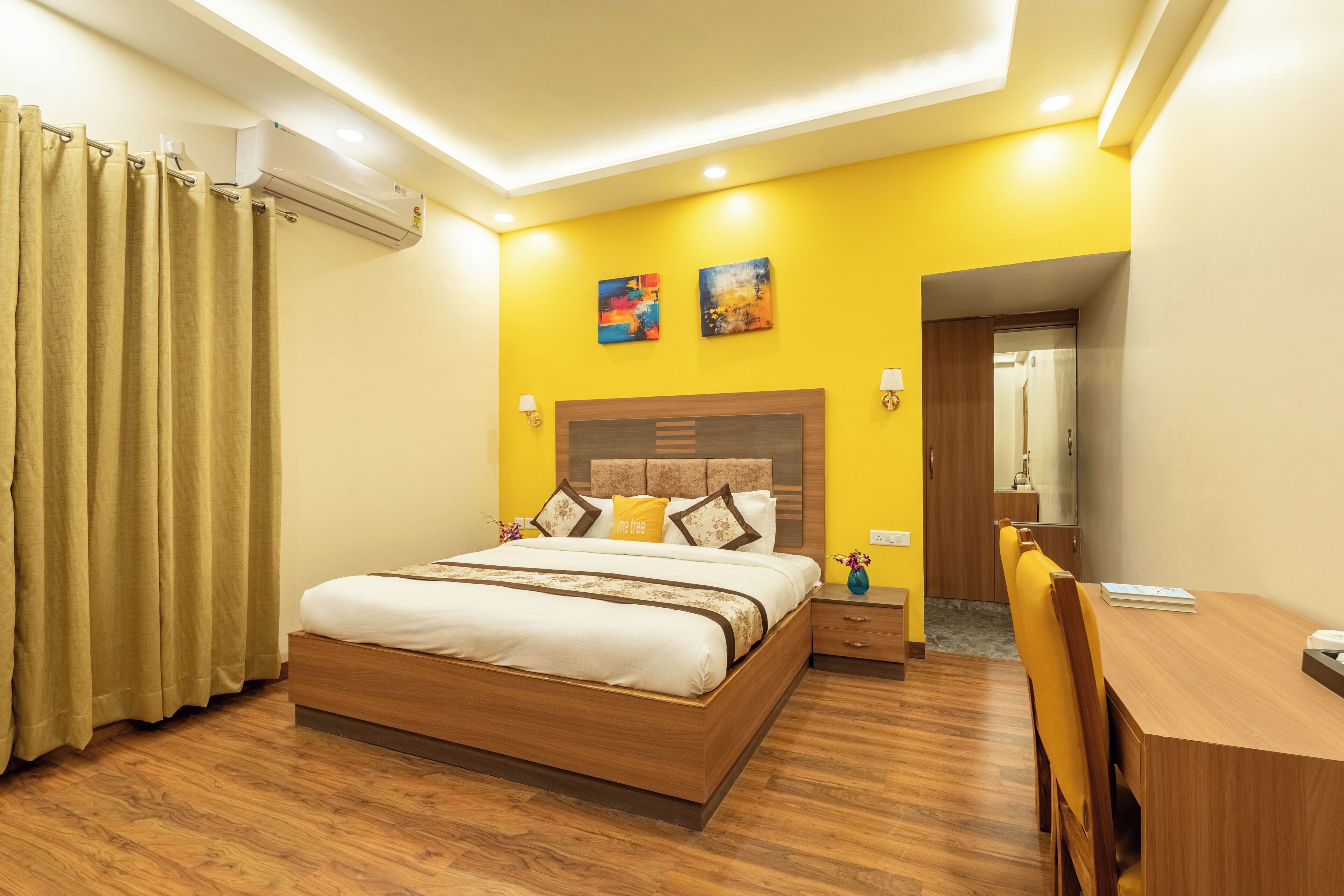 A hotel room with a wooden bed, a desk, and a chair. There is a bathroom visible through an open door.