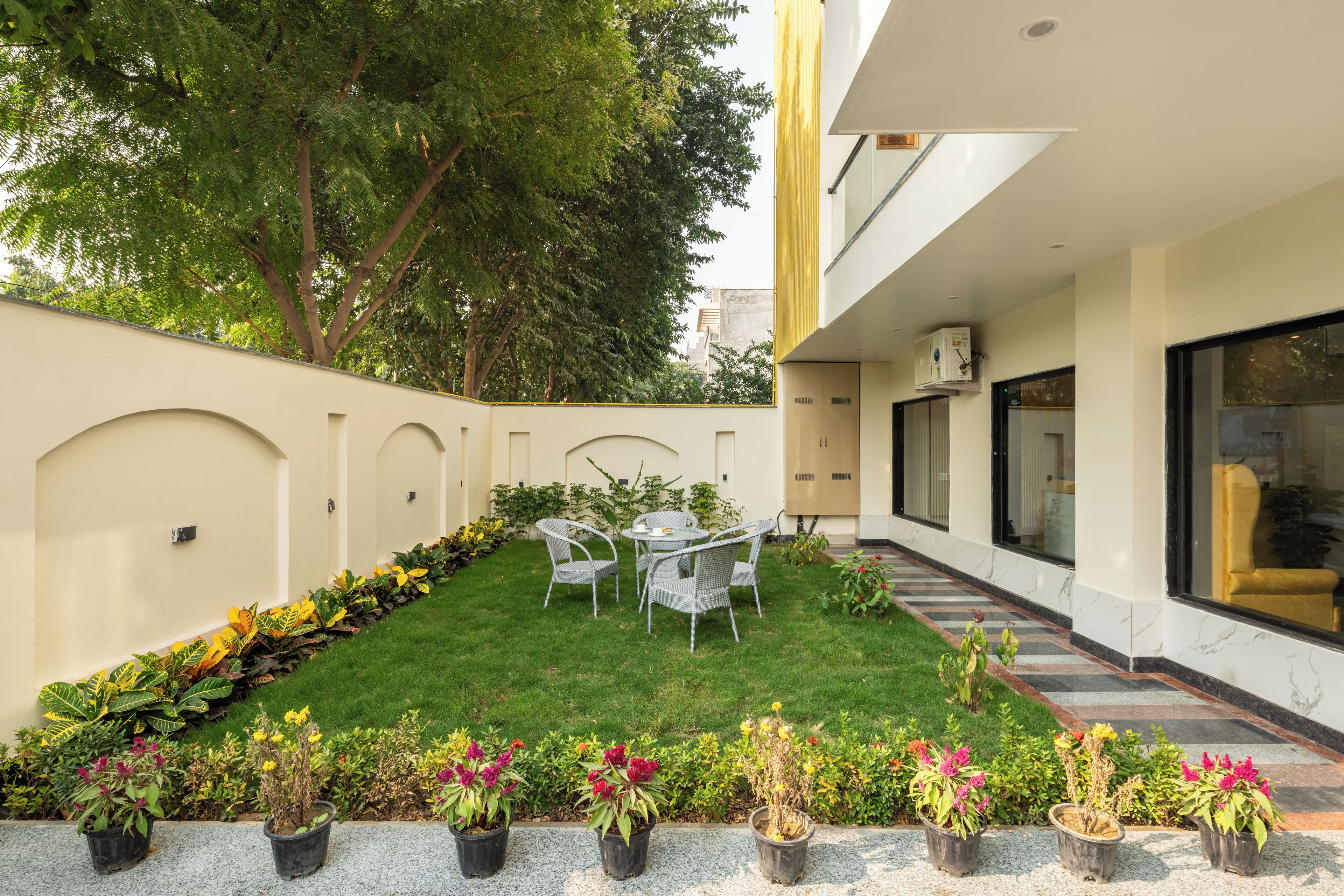 Une terrasse extérieure moderne comprenant un espace repas, un petit jardin et un bâtiment doté de grandes fenêtres.