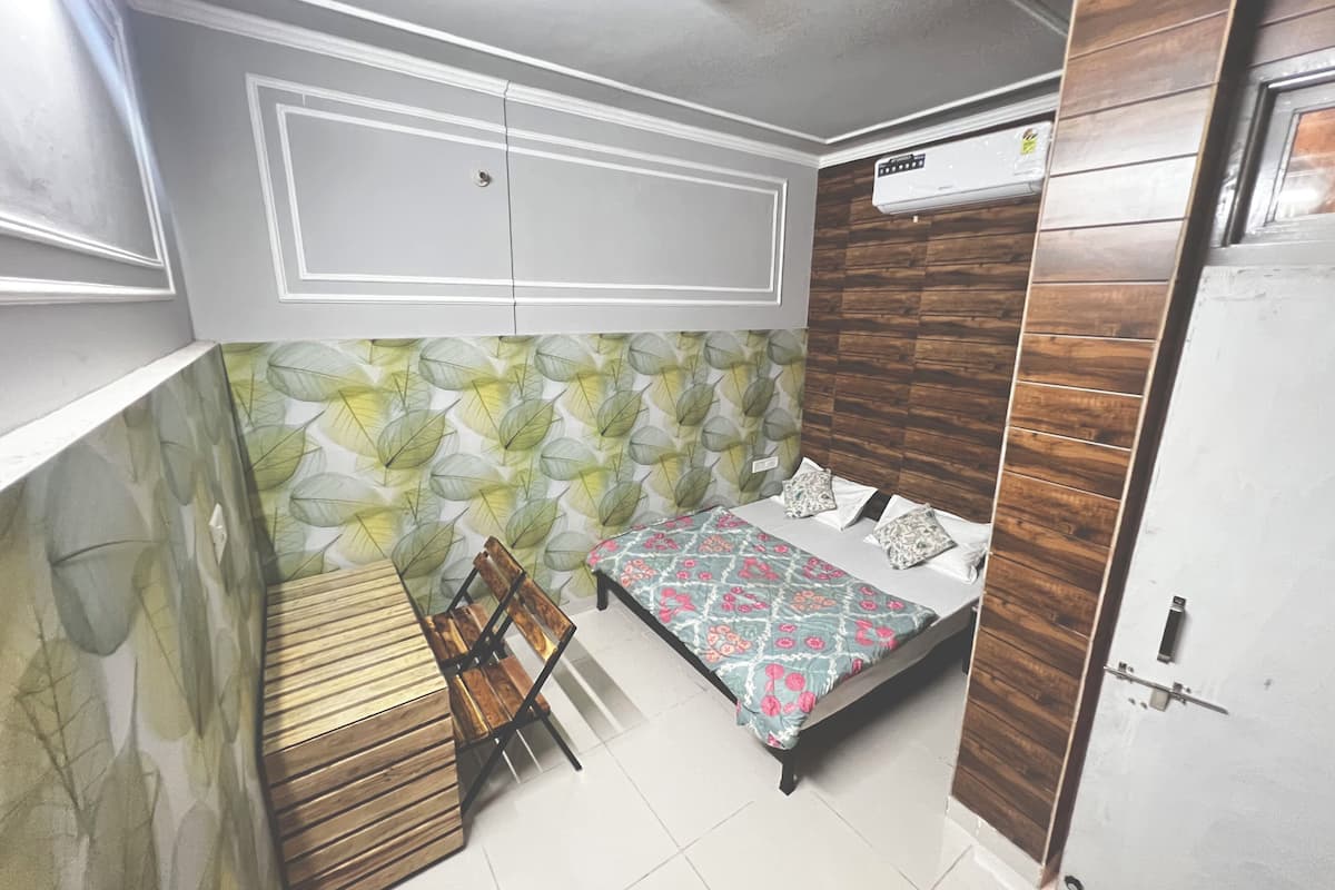 A bedroom with a bed, a wooden bench, a wall with leaf patterns, and a ceiling fan.