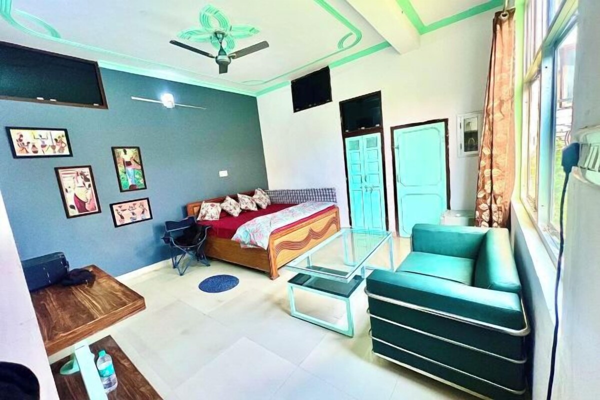 A bedroom with a bed, a glass table, a sofa, a desk, and a ceiling fan.