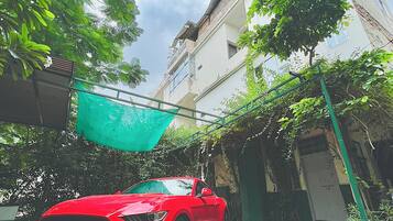 Un auto rojo estacionado en un patio empedrado con un edificio al fondo.
